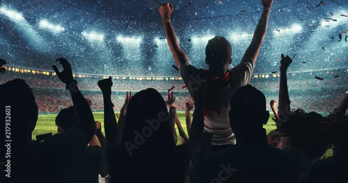 Fototapeta samoprzylepna Fani świętują sukces swojej ulubionej drużyny sportowej na trybunach profesjonalnego stadionu, gdy pada śnieg