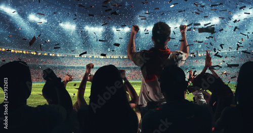 Fans celebrating the success of their favorite sports team on the stands of the professional stadium while it's snowing