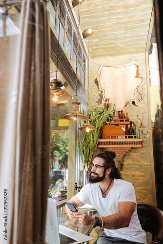 Modern igen. Pleasant positive man using his smartphone while looking into the window © zinkevych