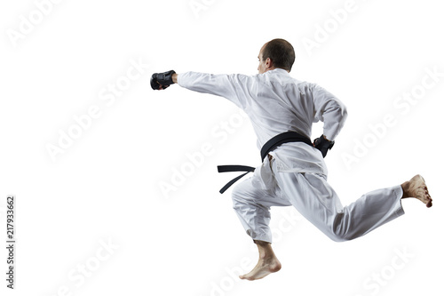 With a black belt, an adult athlete beats with a hand in the jump isolated