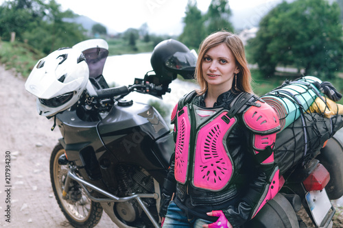 close up portrait girl in pink body armor with big adventure motorcycle with bags and camping equipment, off road travel jorney, traveling together, mountains dirt road and river