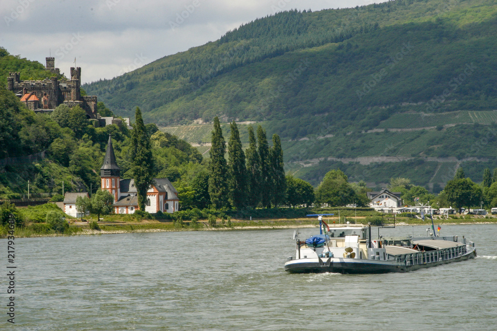Cargo boat floating past castle on the Rhine River