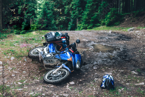 crash adventure motorcycle on dirt forest road, concept of technical support in hard-to-reach places, insurance against crashes, travel problems