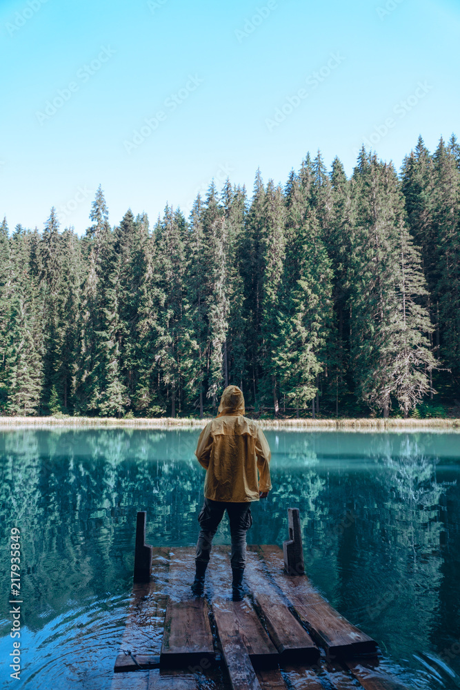 hiker man wearing yellow jacket standing by the mountain lake and looking at the distance, Carpathians Ukraine, vertical photo hiker man wearing yellow jacket standing by the mountain lake and looking at the distance, Carpathians Ukraine, vertical photo