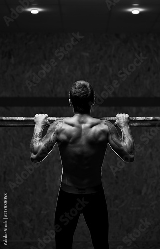 Back view of muscular man with naked torso doing pull up exercise on horizontal bar. Cross training at the gym © pavel_shishkin