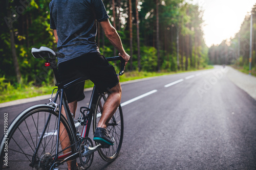 Road bike cyclist  man cycling on empty road in sunset