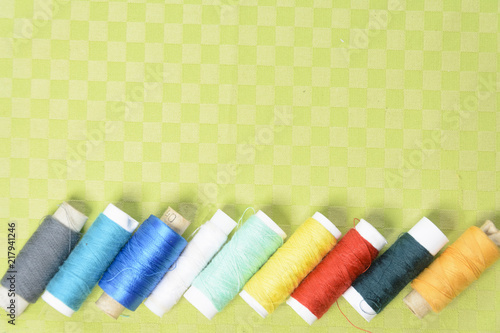 Colorful thread in spools on green background photo