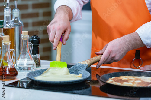 kitchen Preparation: the chef fries fresh pancakes in two pans photo