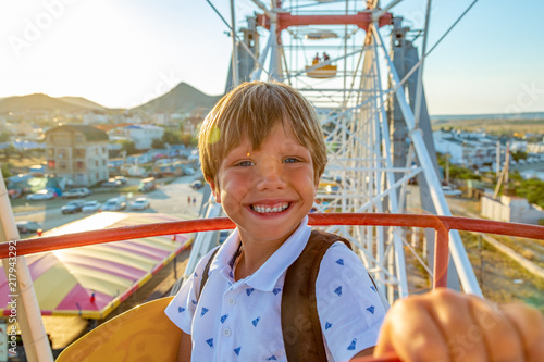 Smilling excited boy enjoying the view from ferris wheel in amusement park