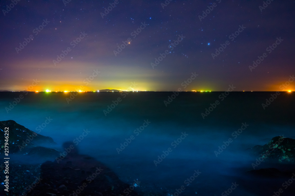 白波寄せる夜の海で星を眺めるセルフポートレート