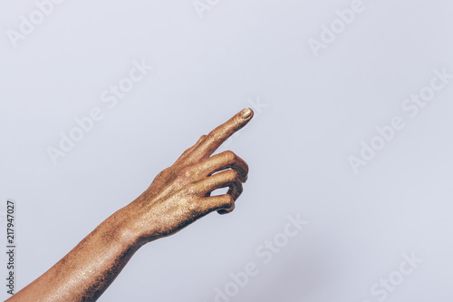 Woman's hand covered with gold sequins pointing finger