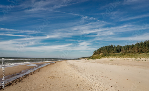 Coastal area in Lithuania Coastal scenery with sandy beach, dunes with marram grass and rough sea on a clear summer day with blue sky.
