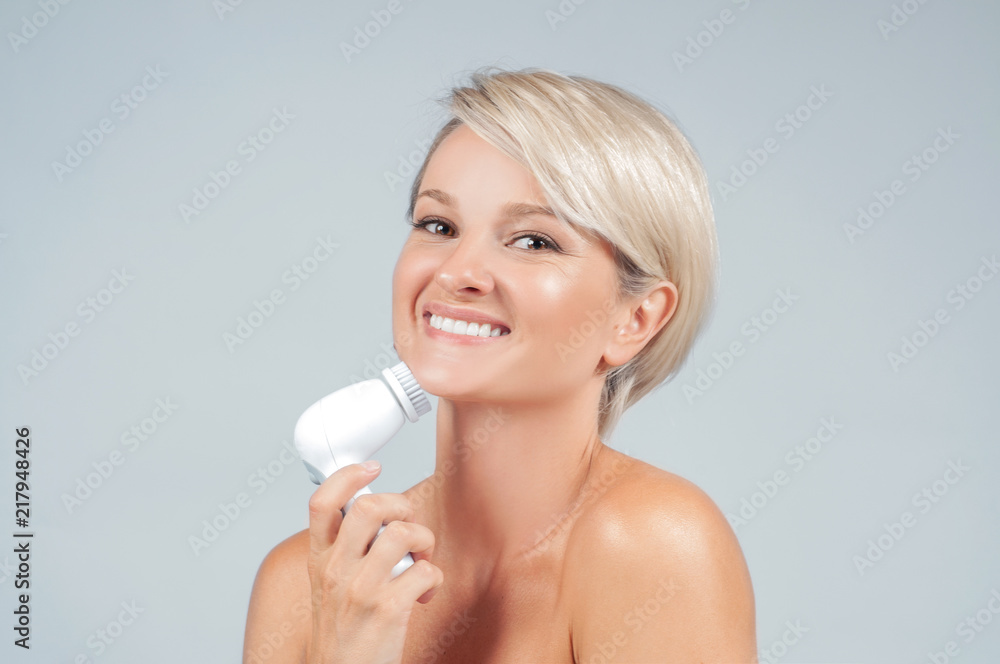 Happy woman cleaning face skin with brush. Beauty and spa. Happy woman cleaning face skin with brush. Beauty and spa.