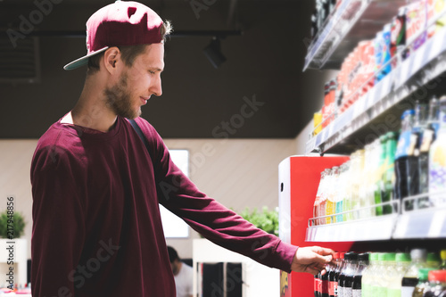 portrait of young bearded man picks some food and drink in supermarket store
