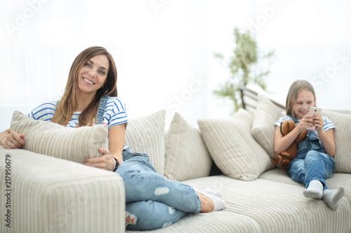 young housewife and her little daughter sitting on the couch