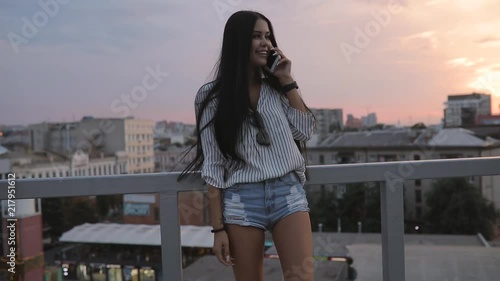 Attractive well-groomed woman talking by smartphone on rooftop