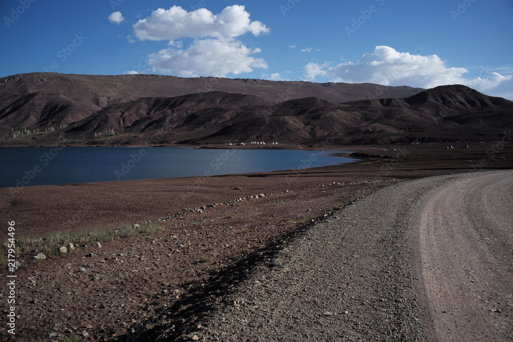 road along bank of a mountain lake with blue sky and clouds road along bank of a mountain lake with blue sky and clouds