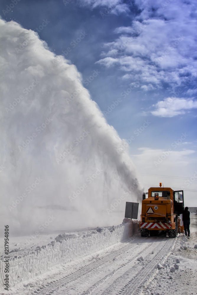 Snow-covered road cleaning by snow removal machine. Snow truck in highway. Snow-covered road cleaning by snow removal machine. Snow truck in highway.