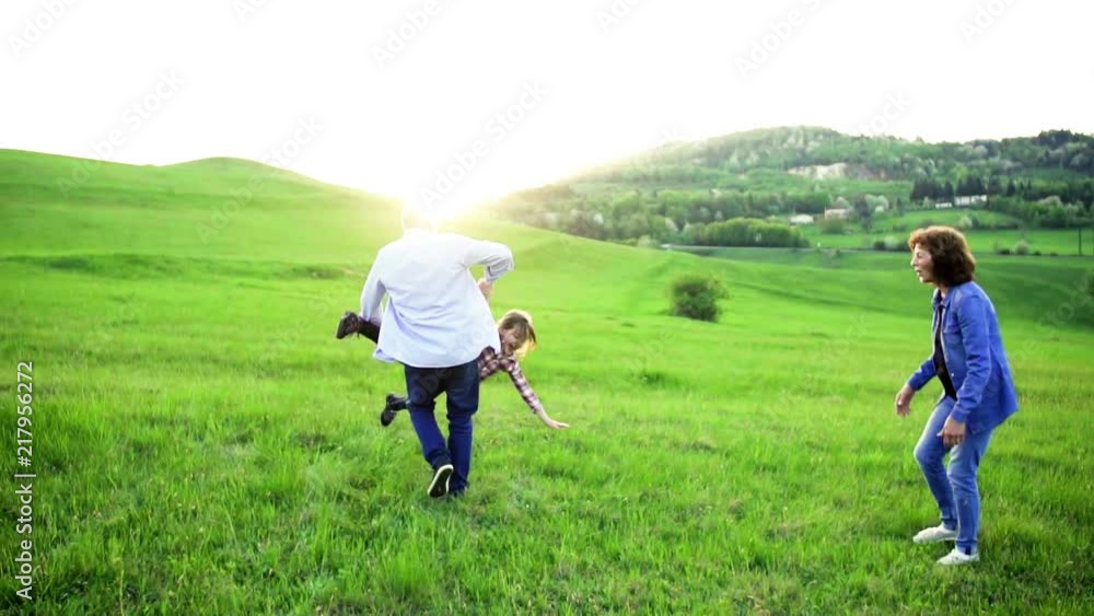 A small girl with her senior grandparents playing outside in nature at sunset. A small girl with her senior grandparents playing outside in nature at sunset.