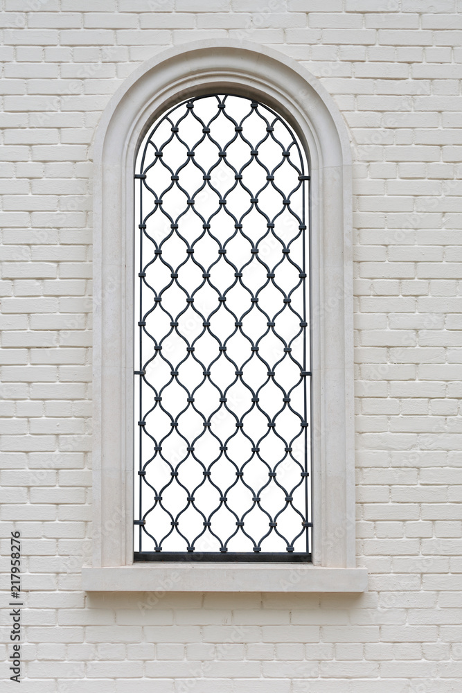 arched window with wrought iron lattice and decorative figures in the brick wall. window isolated with clipping path