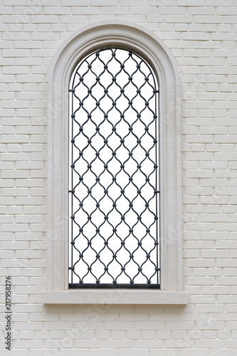 Obraz na płótnie arched window with wrought iron lattice and decorative figures in the brick wall. window isolated with clipping path w salonie