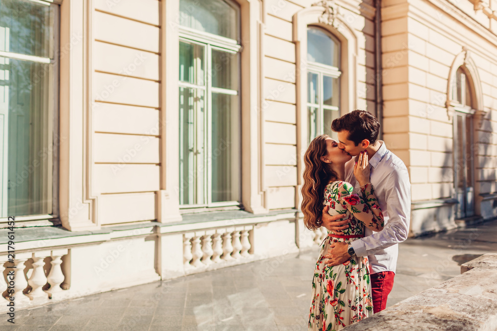 Young happy couple in love hugging and kissing outdoors. Man and woman walking by Pototskykh palace in Lviv Young happy couple in love hugging and kissing outdoors. Man and woman walking by Pototskykh palace in Lviv
