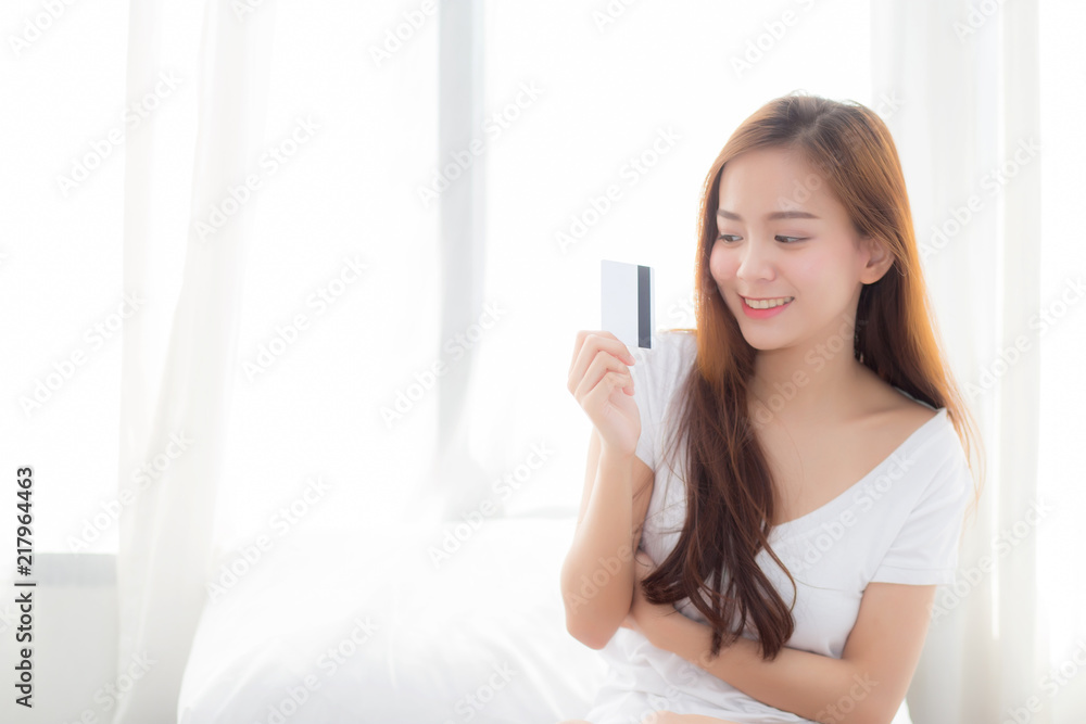 Beautiful portrait young asian woman shopping online with credit card sitting in bedroom, girl with customer purchase of payment online, lifestyle concept. Beautiful portrait young asian woman shopping online with credit card sitting in bedroom, girl with customer purchase of payment online, lifestyle concept.
