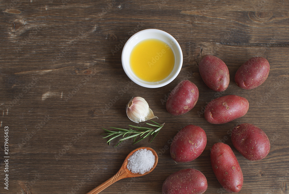 Olive oil porcelain plate Rosemary branch Pepper mix Garlic Seasoning Spices Raw potato Cooking concept Wooden background Top view Copy space Flat lay Olive oil porcelain plate Rosemary branch Pepper mix Garlic Seasoning Spices Raw potato Cooking concept Wooden background Top view Copy space Flat lay