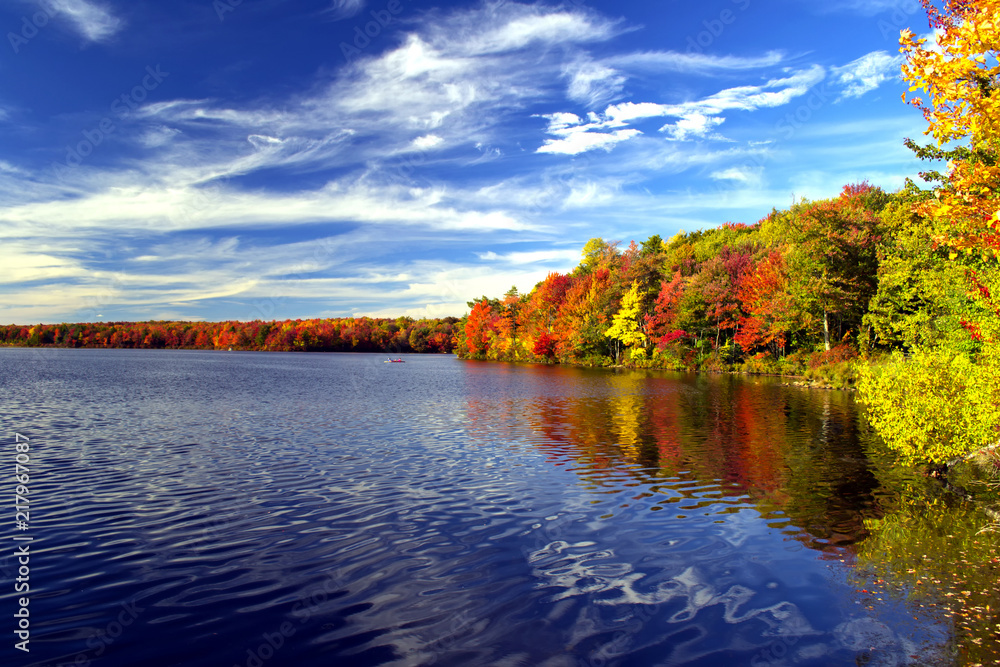 Fototapeta premium Colorful fall foliage surrounds a lake in the Poconos of Pennsylvania.