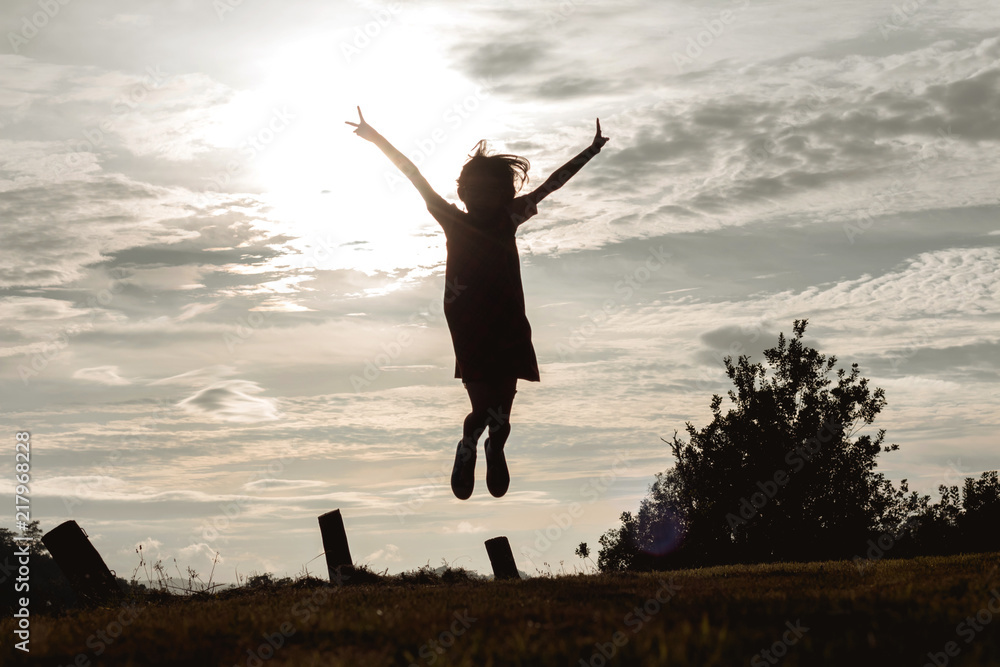 Silhouette of happy child jumping with hands shape on mountain meadow at sunset time Silhouette of happy child jumping with hands shape on mountain meadow at sunset time