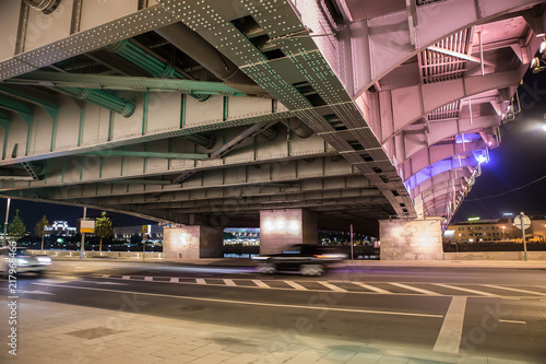 Cars move at night under the bridge in the city