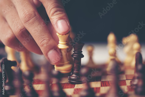 hand of businessman moving chess figure in competition success play. strategy, management or leadership concept