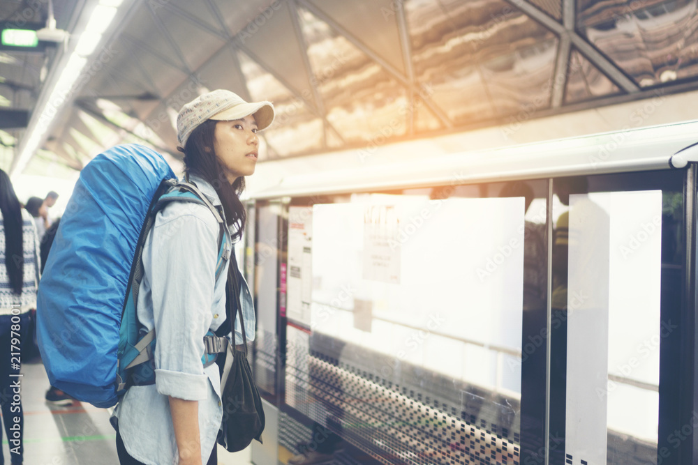 Beautiful young travelers are watching the train schedule.