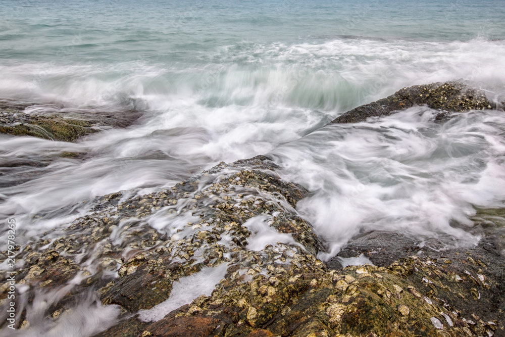 Sea waves crashing to rocks creating foam