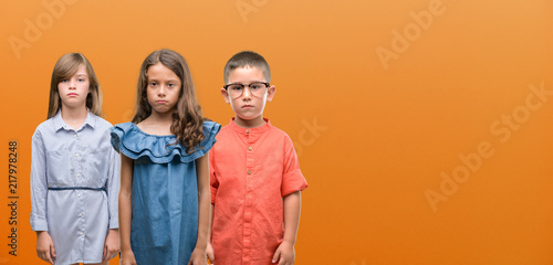 Group of boy and girls kids over orange background with a confident expression on smart face thinking serious