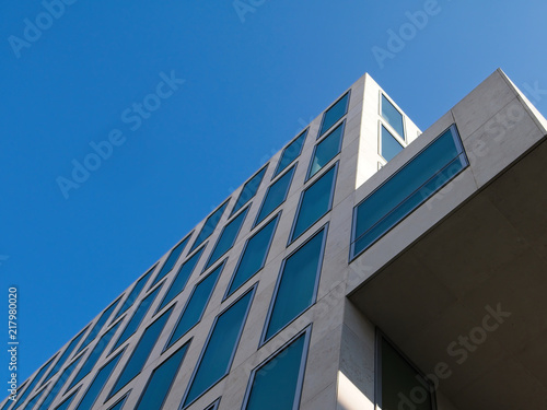 Low angle view of cantilevered contemporary building against blue sky. Diminishing perspective view. 