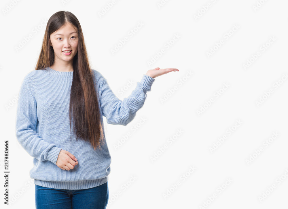 Young Chinese woman over isolated background smiling cheerful presenting and pointing with palm of hand looking at the camera. Young Chinese woman over isolated background smiling cheerful presenting and pointing with palm of hand looking at the camera.