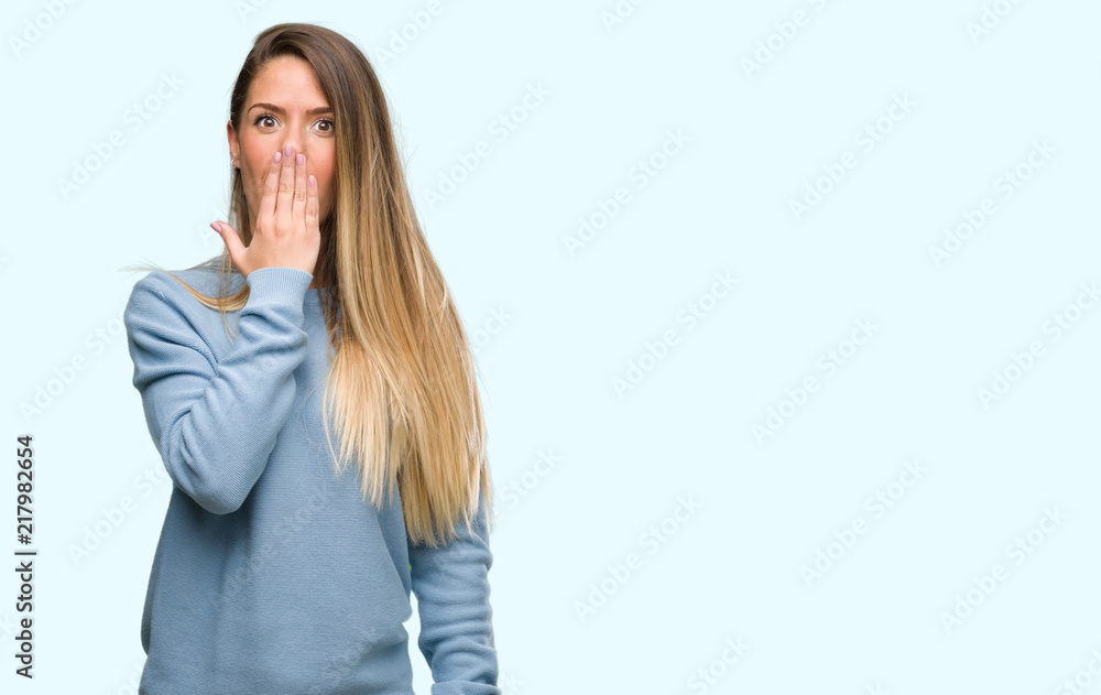 Beautiful young woman wearing sweater and jeans cover mouth with hand shocked with shame for mistake, expression of fear, scared in silence, secret concept Beautiful young woman wearing sweater and jeans cover mouth with hand shocked with shame for mistake, expression of fear, scared in silence, secret concept