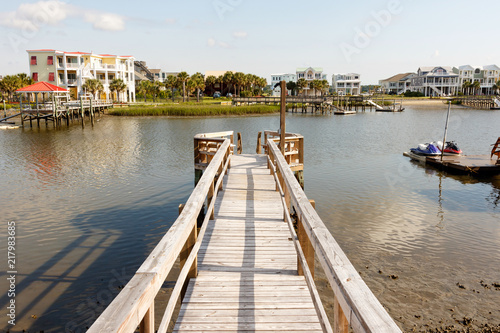 Long wooden dock into the inter coastal waterway in North Carolina, with luxury vacation homes and personal water craft