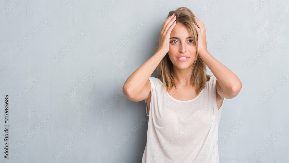 Beautiful young woman standing over grunge grey wall stressed with hand on head, shocked with shame and surprise face, angry and frustrated. Fear and upset for mistake. Beautiful young woman standing over grunge grey wall stressed with hand on head, shocked with shame and surprise face, angry and frustrated. Fear and upset for mistake.
