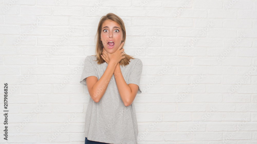 Beautiful young woman over white brick wall shouting and suffocate because painful strangle. Health problem. Asphyxiate and suicide concept. Beautiful young woman over white brick wall shouting and suffocate because painful strangle. Health problem. Asphyxiate and suicide concept.