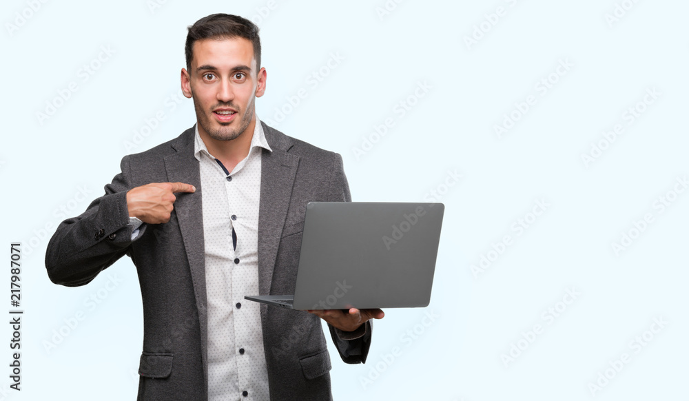 Handsome young man using computer laptop with surprise face pointing finger to himself Handsome young man using computer laptop with surprise face pointing finger to himself