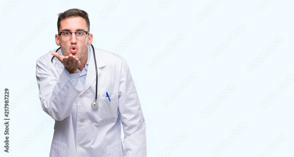 Handsome young doctor man looking at the camera blowing a kiss with hand on air being lovely and sexy. Love expression. Handsome young doctor man looking at the camera blowing a kiss with hand on air being lovely and sexy. Love expression.