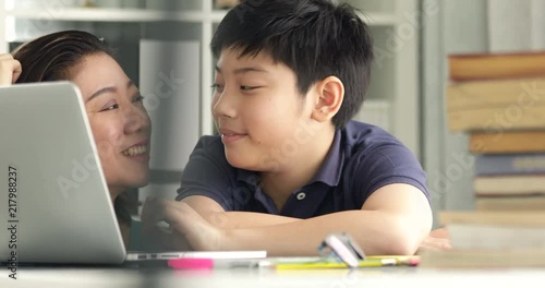 Cute asian mother helping your son doing your homework at home with smile face together.