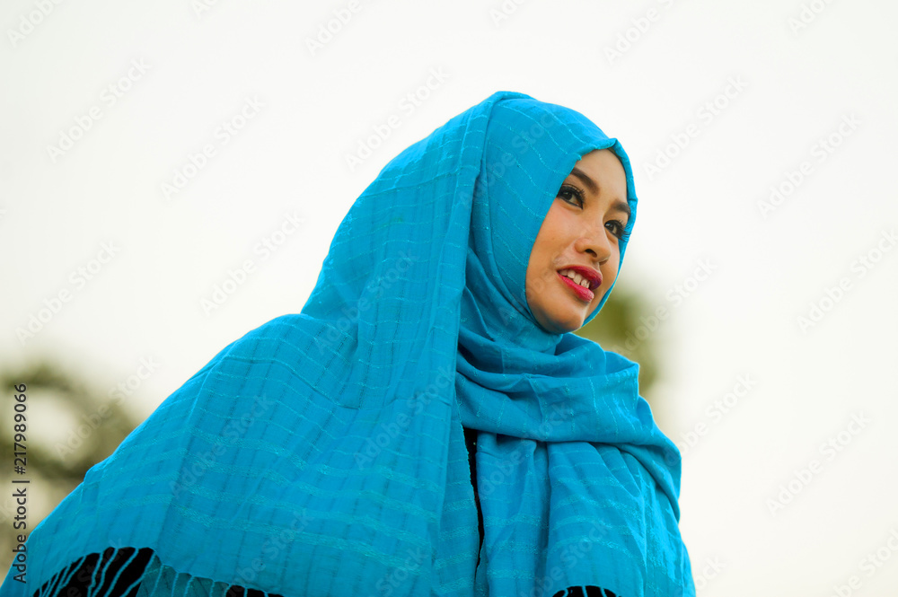 Fototapeta premium isolated white background portrait of young beautiful and happy Asian woman outdoors in blue hijab muslim head scarf smiling cheerful looking away