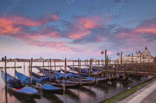 Gondolas parked in Venice at sunset with the Santa Maria della Salute church in the background