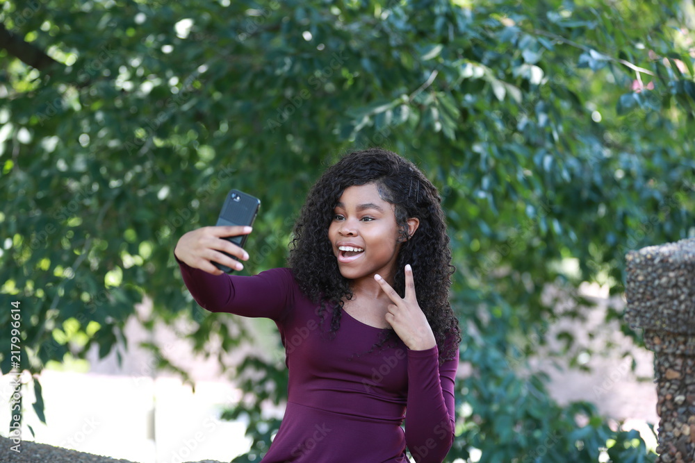 Cheerful black woman gesturing victory and taking selfie Cheerful black woman gesturing victory and taking selfie