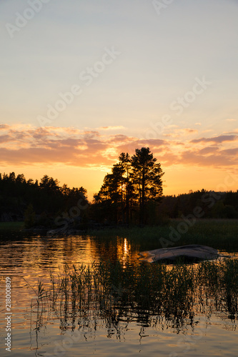 Sunset on the lake in the forest. Beautiful sunset. The sun goes behind the top of the trees on the lake.