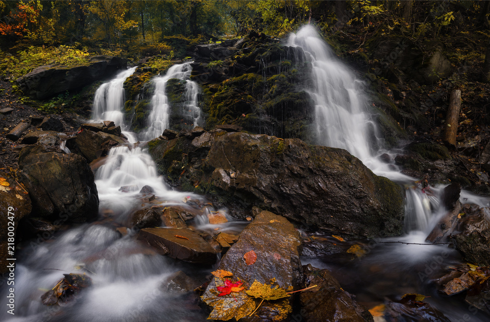 Autumn Forest Landscape With Beautiful Falling Cascades Of Creek And And Colored Leaves On The Stones. Cold Mountain Stream Among The Stones With Moss And Leaves In The Water. Great Autumn Waterfal.