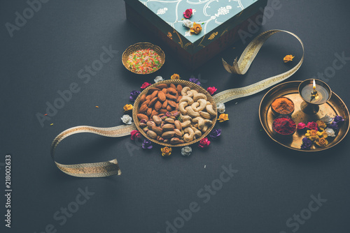 Fototapeta Naklejka Na Ścianę i Meble -  Raksha bandhan Festival greetings: conceptual Rakhi made using a plate full dry fruits like Cashew, pistachio, almond with fancy band and pooja Thali. selective focus